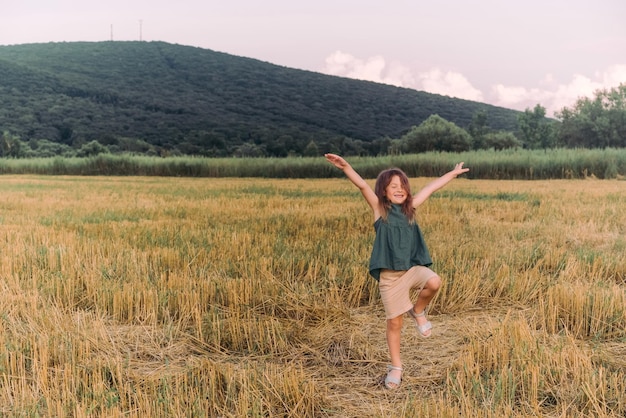Happy little girl celebrating holding out her hands in a yellow field High quality photo