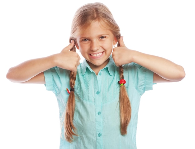 Happy little girl child standing isolated over white background Looking camera showing thumbs up Lifestyle and people concept