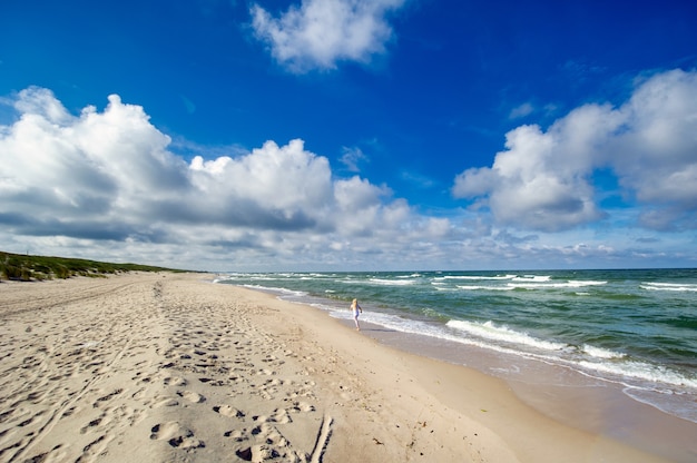 리투아니아에서 Curonian 침에 발트 해 해변에서 옷에 행복 한 어린 소녀.