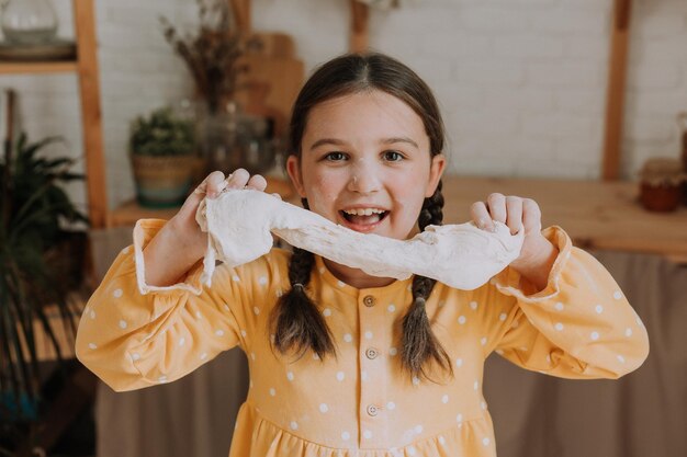 Happy little girl cooks a pie in the kitchen in a cotton dress. High quality photo