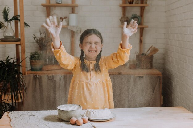 happy little girl cooks a pie in the kitchen in a cotton dress