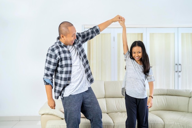 Happy little girl dancing with her father at home