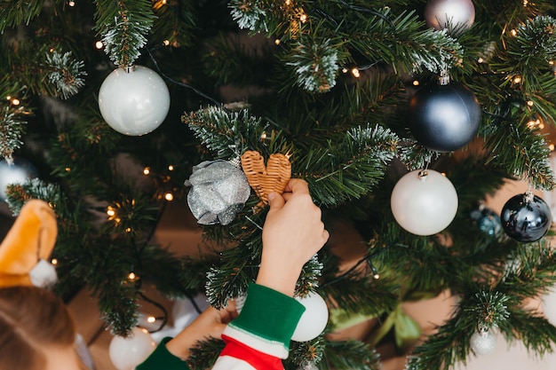 Happy little girl decorate christmas tree at home. winter holidays and people concept