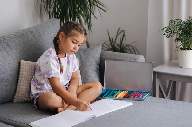 Happy little girl draws in album at home five year old girl draws picture after kindergarten living