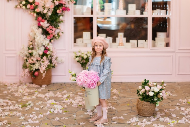 Happy little girl in a dress and in beret with a bouquet of pink peonies 
Mothers Day