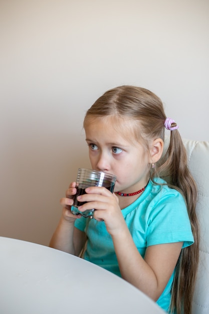 Happy little girl drinking soda from glass