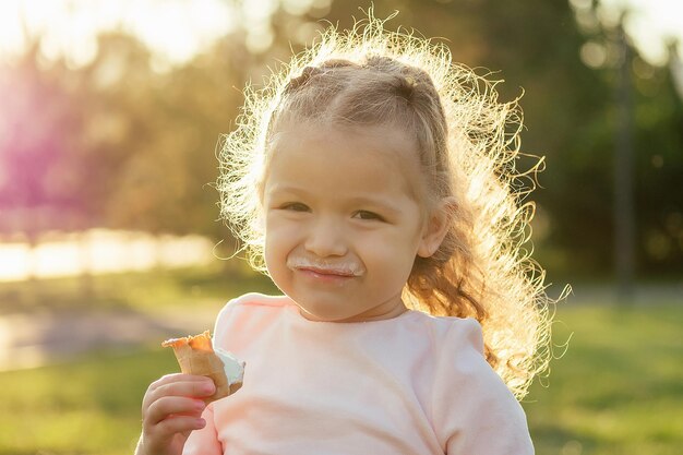 Happy and little girl eating ice cream in summer park