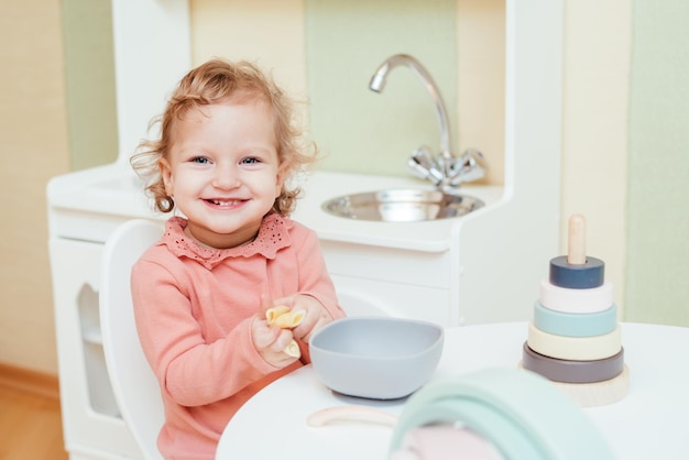 Happy little girl eating pasta in kindergarten