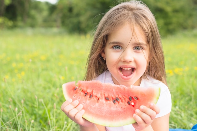 Foto bambina felice che gode dell'anguria nel parco