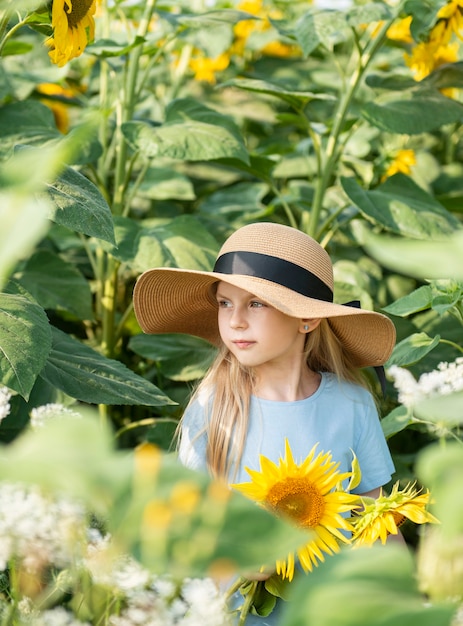 Happy little girl on the field of sunflowers in summer