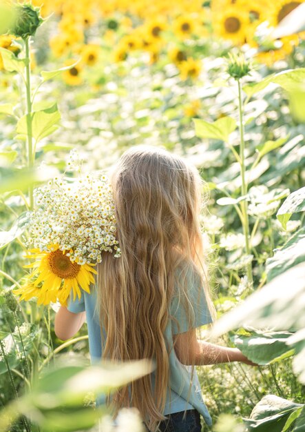 Bambina felice sul campo di girasoli in estate.