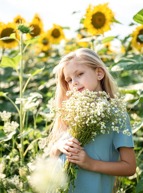 Happy little girl on the field of sunflowers in summer.