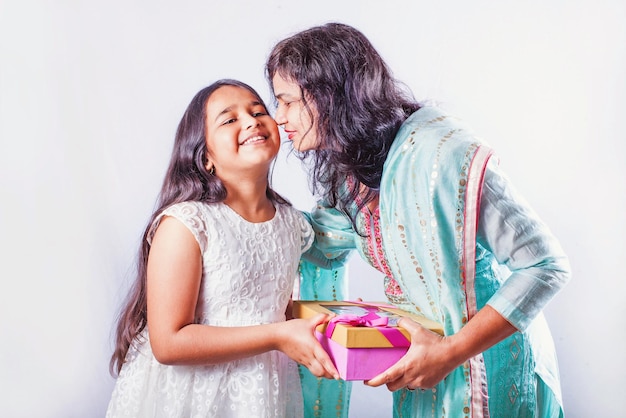 Happy little girl giving gift to her mother who is kissing her