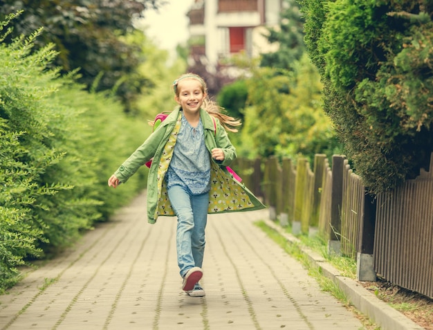 幸せな小さな女の子が学校から家に帰る