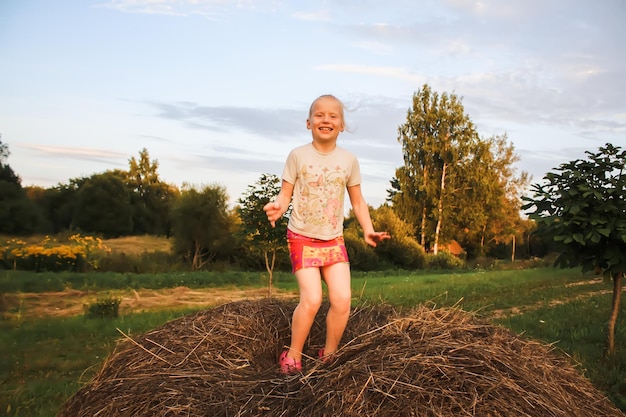 Happy little girl on a haystack in the countryside