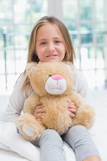 Happy little girl holding her teddy 