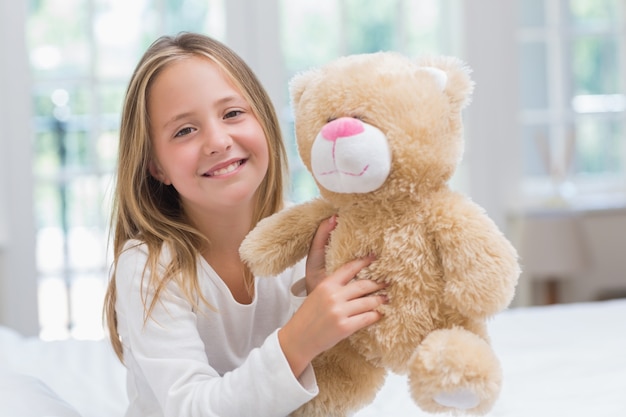 Happy little girl holding her teddy 