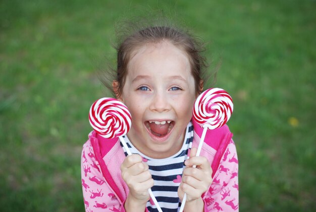 Happy little girl holding lollipop swirl candy. Summer, having fun. 