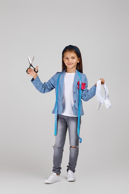 Happy little girl holding tape measure and scissors