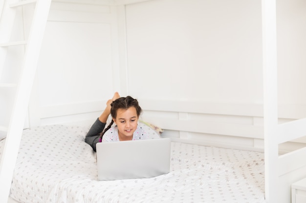 Happy little girl at home working with a laptop