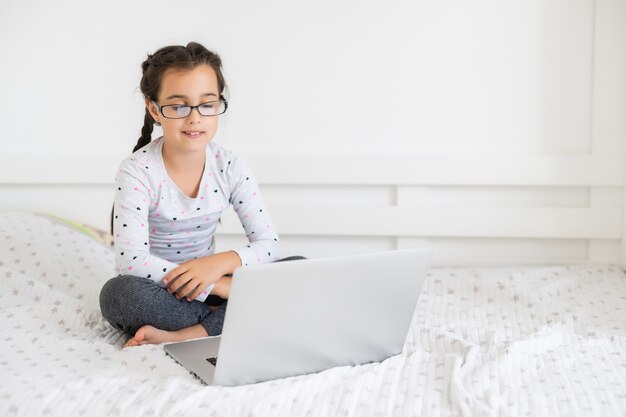 Foto bambina felice a casa che lavora con un laptop