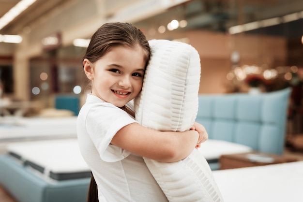 Happy Little Girl Hugging Pillow in Mattress Store