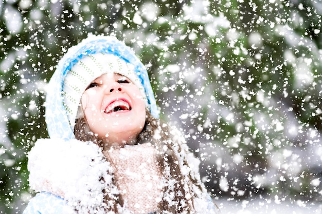 행복한 어린 소녀가 겨울 숲에서 하늘을 올려다보고 있다