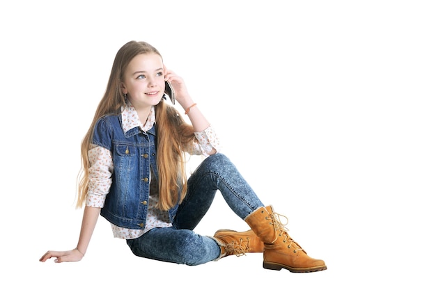 Happy little girl in jeans talking on phone