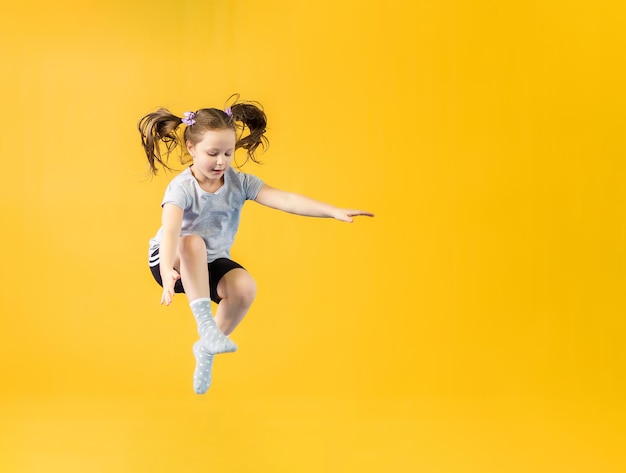Фото Счастливая девочка прыгает на желтом фоне