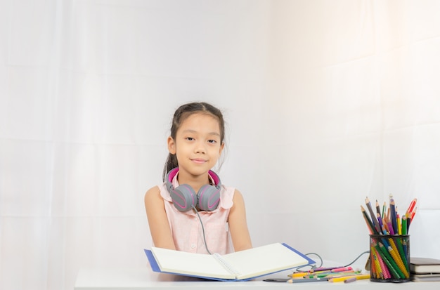 Happy little girl kid standing with headphones and hand holding book