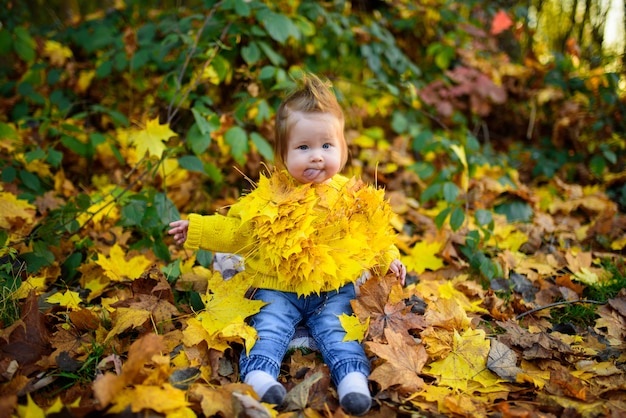 Happy little girl laughs and plays outdoors. On the neck there is a necklace of autumn leaves.