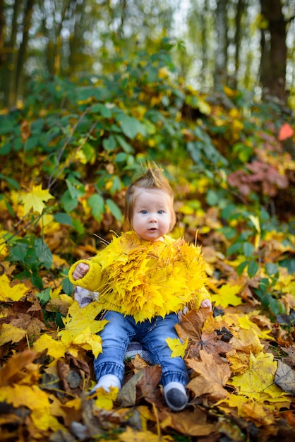 Happy little girl laughs and plays outdoors. On the neck there is a necklace of autumn leaves.