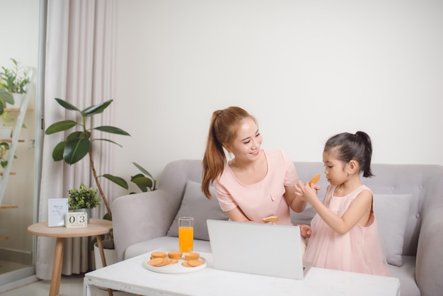 彼女の母親と一緒にラップトップを見て幸せな少女