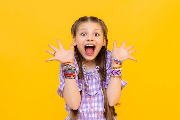 The happy little girl opened her mouth wide with delight and spread her fingers in different directions the child dressed up in colorful beaded bracelets beading for children and teenagers