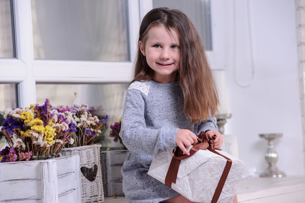 선물 상자를 여는 행복 한 어린 소녀.