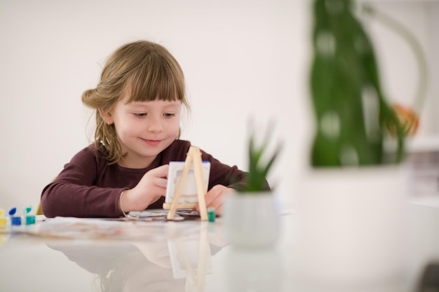 happy little girl painting on canvas image at home