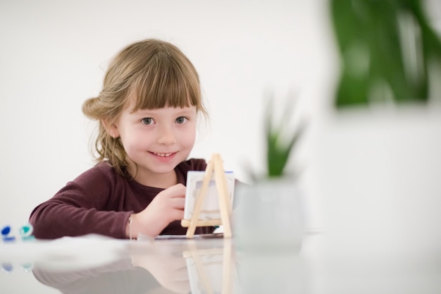 happy little girl painting on canvas image at home