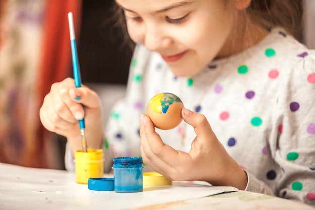 Happy little girl painting easter egg