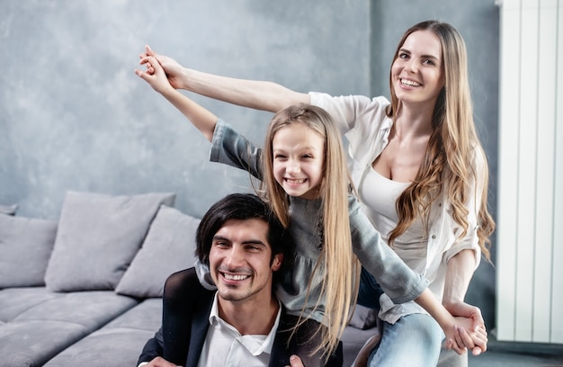 Happy little girl play with her mother and father on the sofa