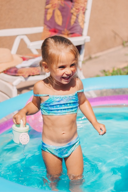 Счастливая маленькая девочка, играя в детском надувном бассейне