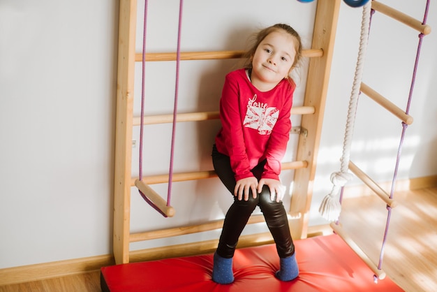 Happy little girl playing on the monkey bars and have fun at home