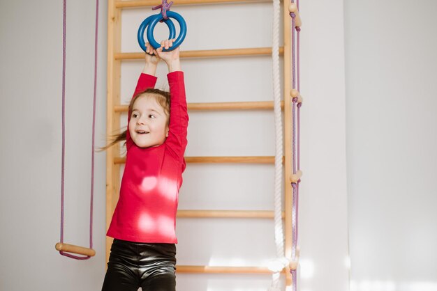 Happy little girl playing on the monkey bars and have fun at home