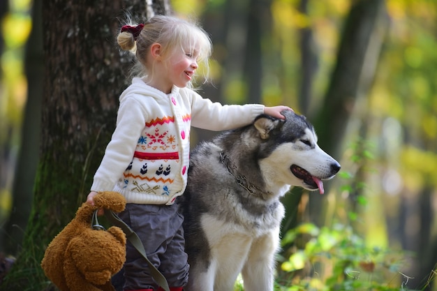 Happy little girl playing with big dog in garden.