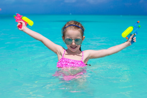 Happy little girl playing with toys during caribbean vacation