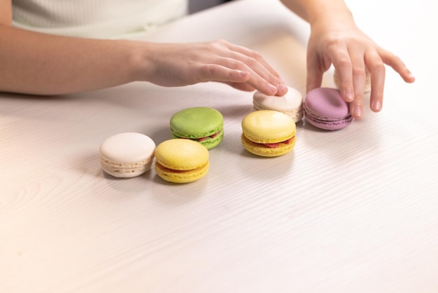 Happy little girl plays with dessert macarons on home background kid girl plays macarons cookie