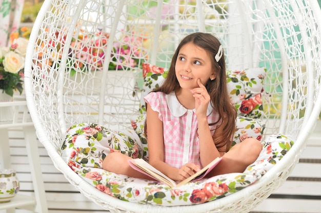 Happy little girl reading book on swing