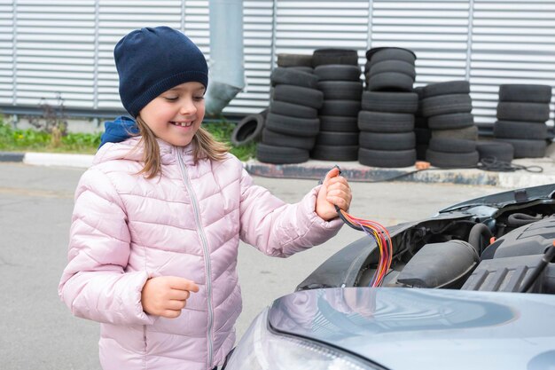 Happy little girl repairing an electrician in a car Car service