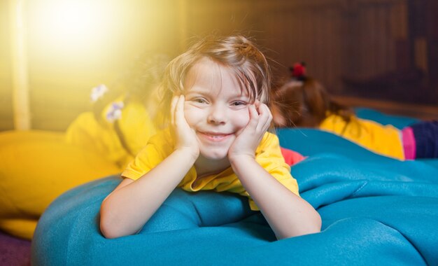 子供の娯楽センターの椅子のバッグで休んでいる幸せな少女