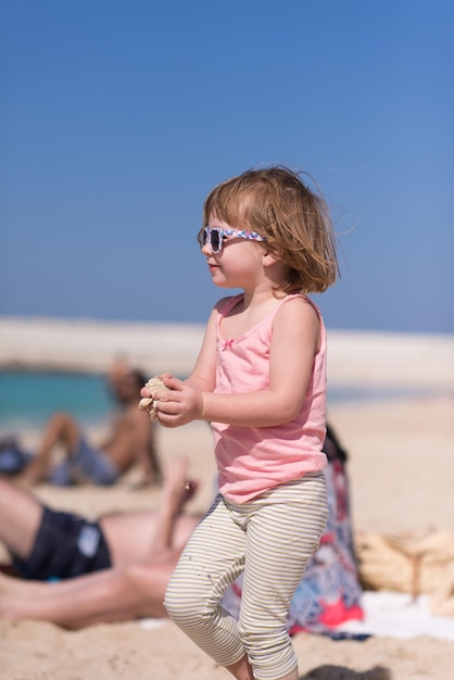 夏の海辺で幸せな少女。夏休み中にビーチで愛らしい少女。海や海でサングラスをかけた幸せな赤ちゃん