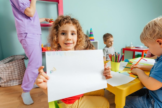 Happy little girl showing her drawing to the camera